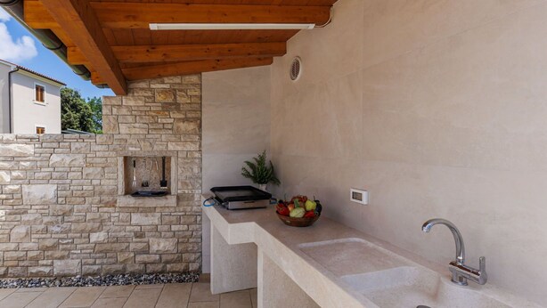 An outdoor kitchen with a stone wall, a built-in grill, and a sink. - Stunning  villa for 8 people with A/C, WIFI, private pool, TV and terrace (Šegotici)