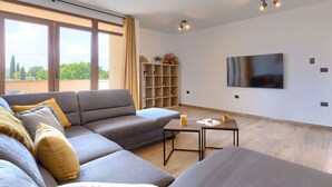 A modern living room with a grey sectional sofa, a small coffee table, and a TV mounted on the wall. - Stunning  villa for 8 people with A/C, WIFI, private pool, TV and terrace (Šegotici)