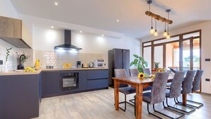 A modern kitchen with a central island, built-in appliances, and a dining area with a wooden table and chairs. - Stunning  villa for 8 people with A/C, WIFI, private pool, TV and terrace (Šegotici)
