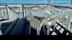 Ein Balkon mit Tisch und Stühlen mit Blick auf einen Strand.