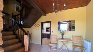 A spacious living area with a wooden staircase, a dining table with chairs, and a view into the kitchen. - RURAL TYPICAL ASTURIAS'S HOME (Prunales)