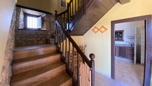A wooden staircase with stone walls and a kitchen area visible in the background. - RURAL TYPICAL ASTURIAS'S HOME (Prunales)