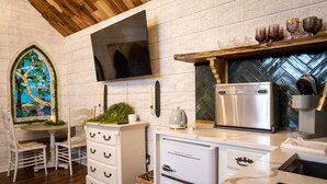 Une cuisine moderne dotée d’un réfrigérateur en acier inoxydable, d’un téléviseur à écran plat fixé au mur et d’un plafond en bois.