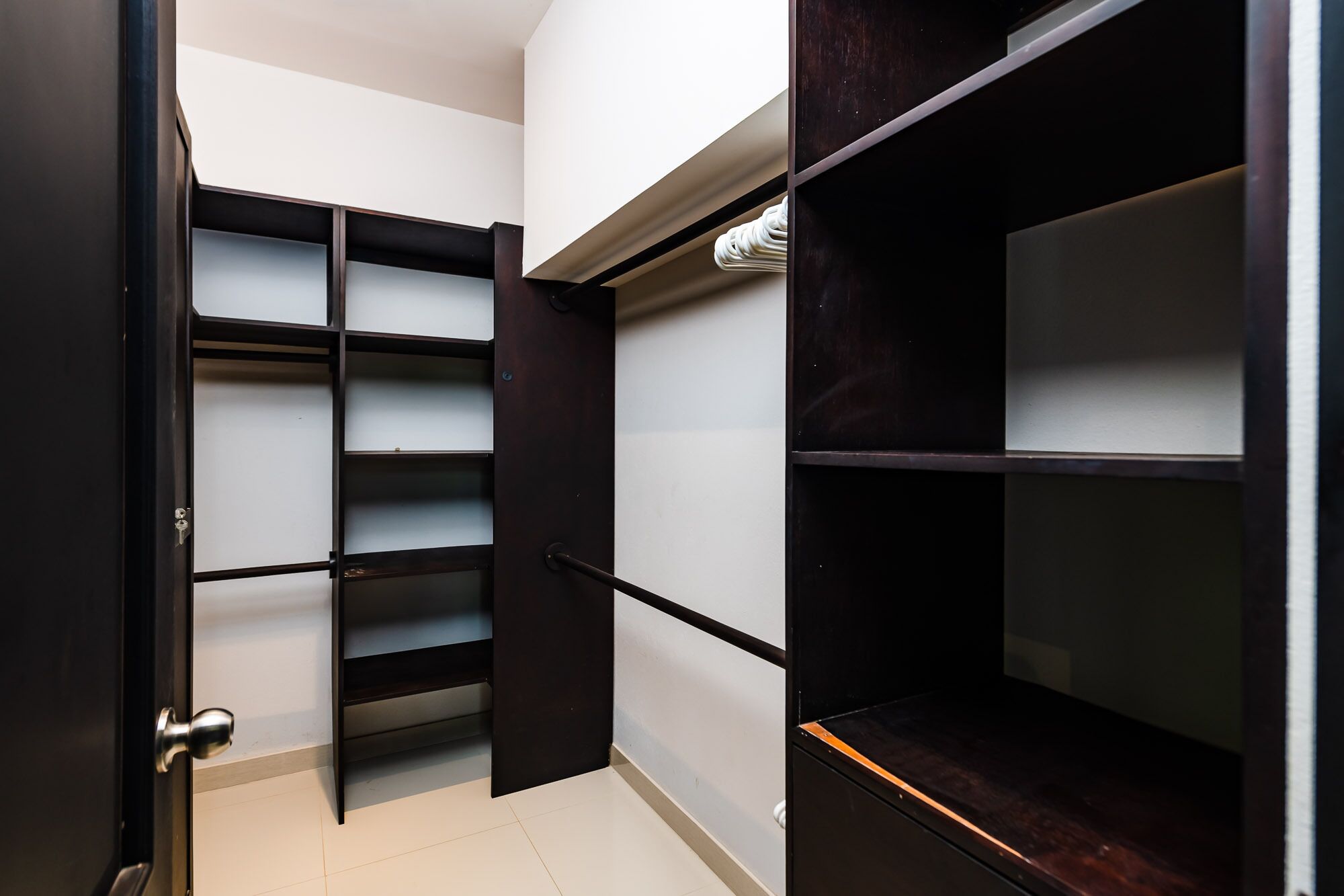 A walk-in closet with open doors, revealing shelves and hanging space.