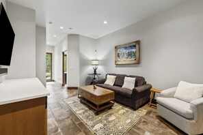 Ein modernes Wohnzimmer mit Sofa, Sessel, Couchtisch und einem Bild an der Wand.