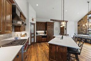 A spacious kitchen with wooden cabinets, a central island, and a dining area with a chandelier. - 1.5 mi to Gondola/Town, 5-Star Perfection, Views (Breckenridge)