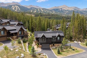 Zona residencial con varias casas, rodeada por un bosque y montañas al fondo.