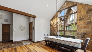 Een eetruimte met een houten tafel en stoelen, een kroonluchter en een stenen muur.