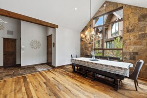 Ein Essbereich mit Holztisch und -stühlen, einer Kristallleuchter und einer Steinwand.