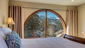 A hotel room with a large arched window offering a mountain view. - Amazing Views | Walk or Free Shuttle to Town (Breckenridge)