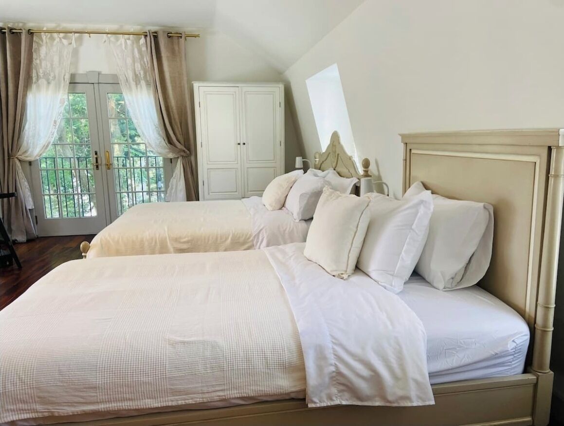 Un dormitorio con dos camas, un armario y una ventana con cortinas.