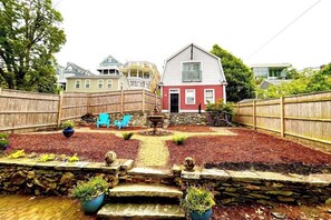 Stroll through the serene backyard, surrounded by lush potted plants and a soothing fountain.