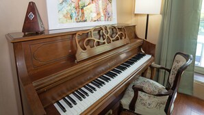A grand piano with a decorative stand, a chair with floral upholstery, and a framed artwork above the piano. - Spacious & Quiet 5 beds, 3.5 bathroom home away from home in Katy, Texas (Katy)