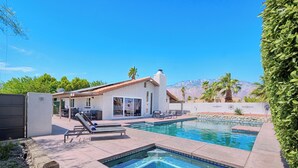 Ein modernes Haus mit Pool, Terrassenmöbel und Blick auf die Berge.
