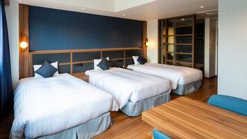 Habitación de hotel con dos camas, cabecero de madera, una mesa y una silla azul.