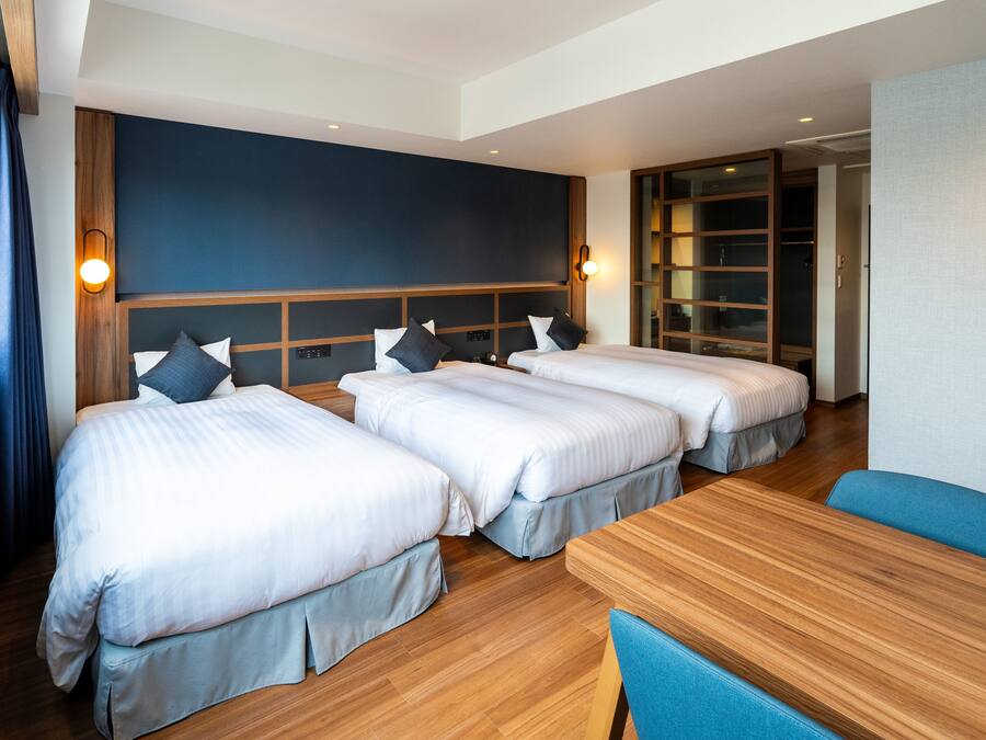 Habitación de hotel con dos camas, cabecero de madera, una mesa y una silla azul.
