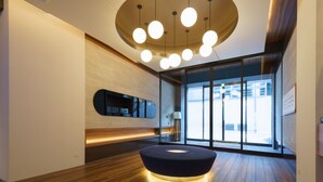A modern interior with a wooden floor, a circular seating area, a wall-mounted TV, and a large window with a view.
