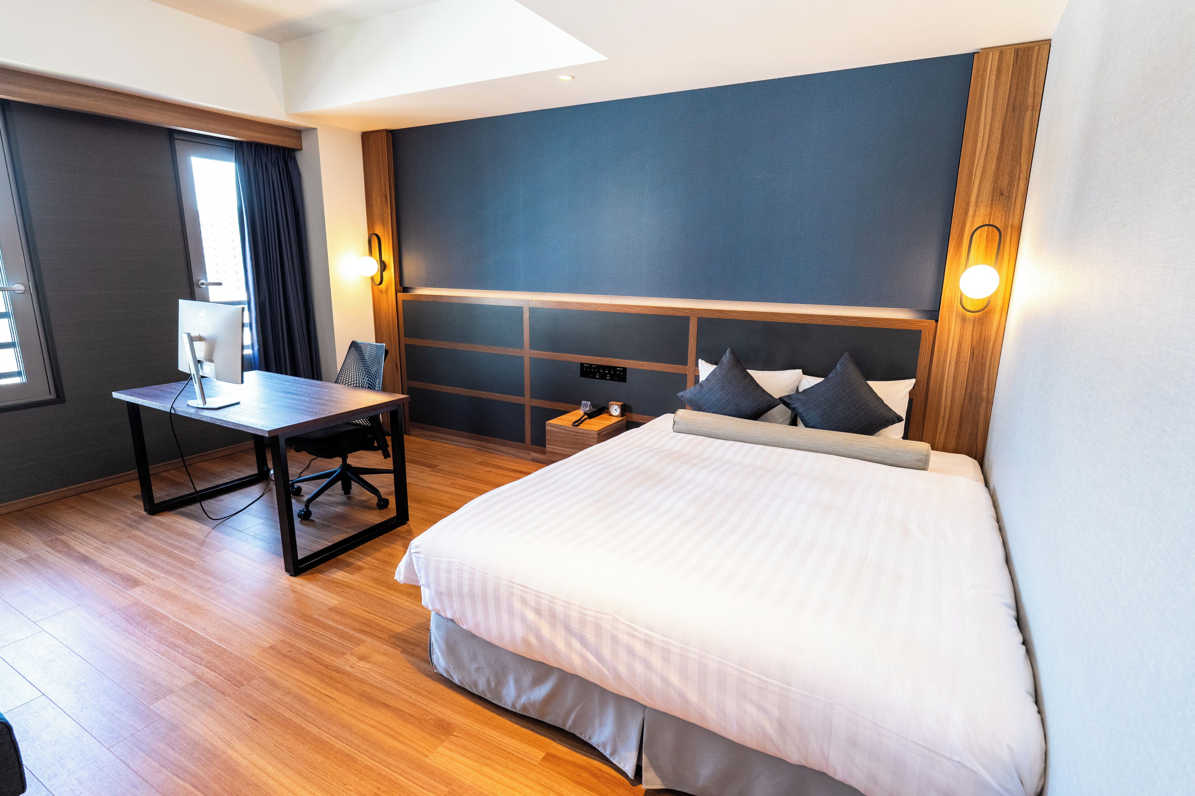 Une chambre d’hôtel moderne, dotée d’un grand lit, d’un bureau et d’une chaise.