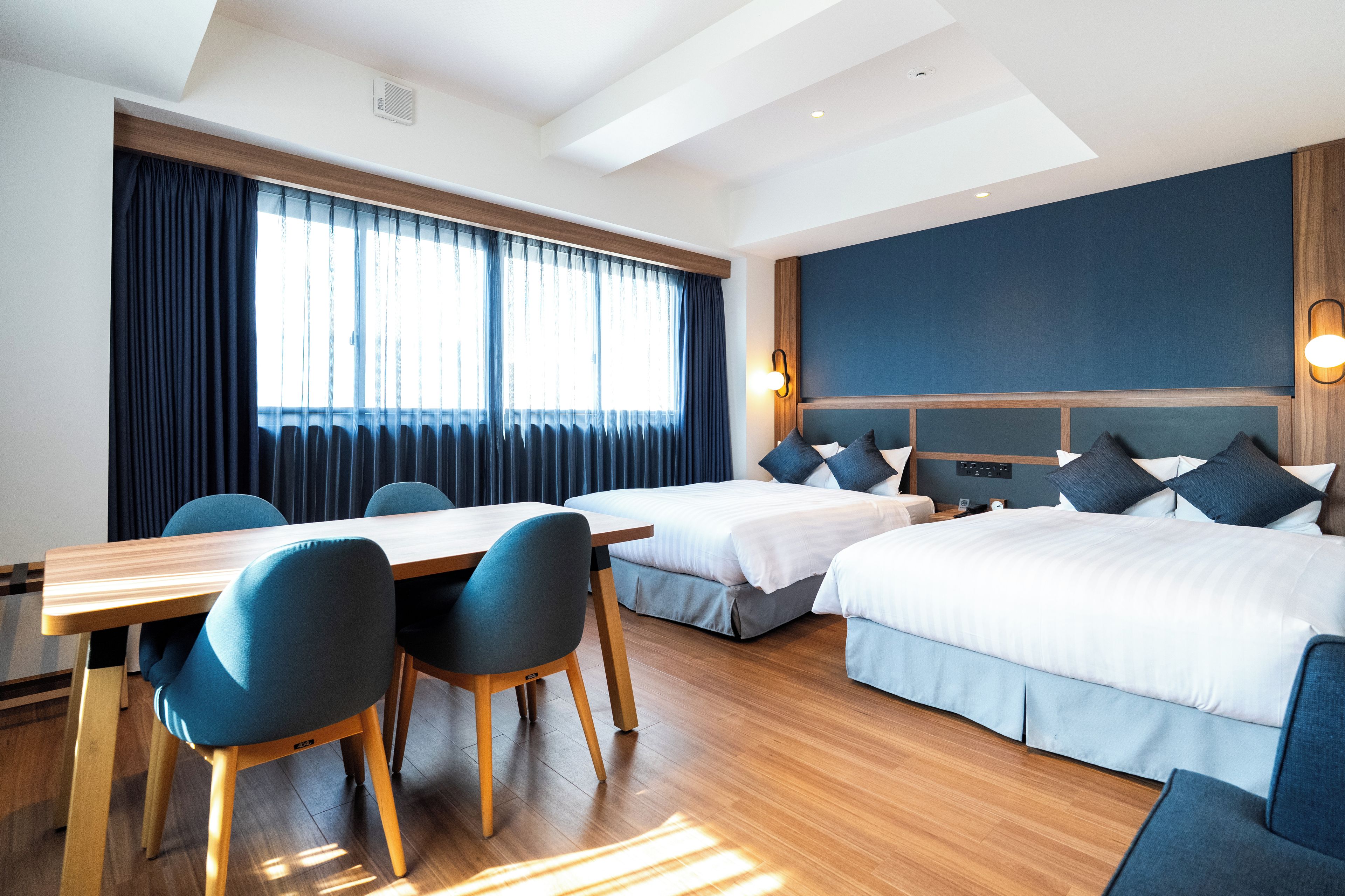 Een hotelkamer met twee bedden, een eettafel en stoelen.