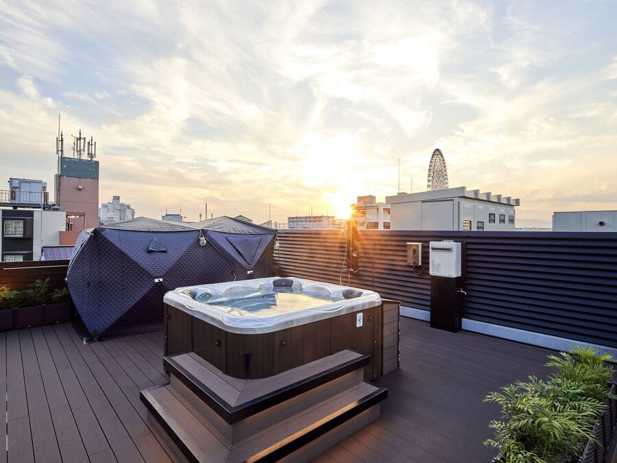 A rooftop with a hot tub, a geometric structure, and a Ferris wheel in the background.