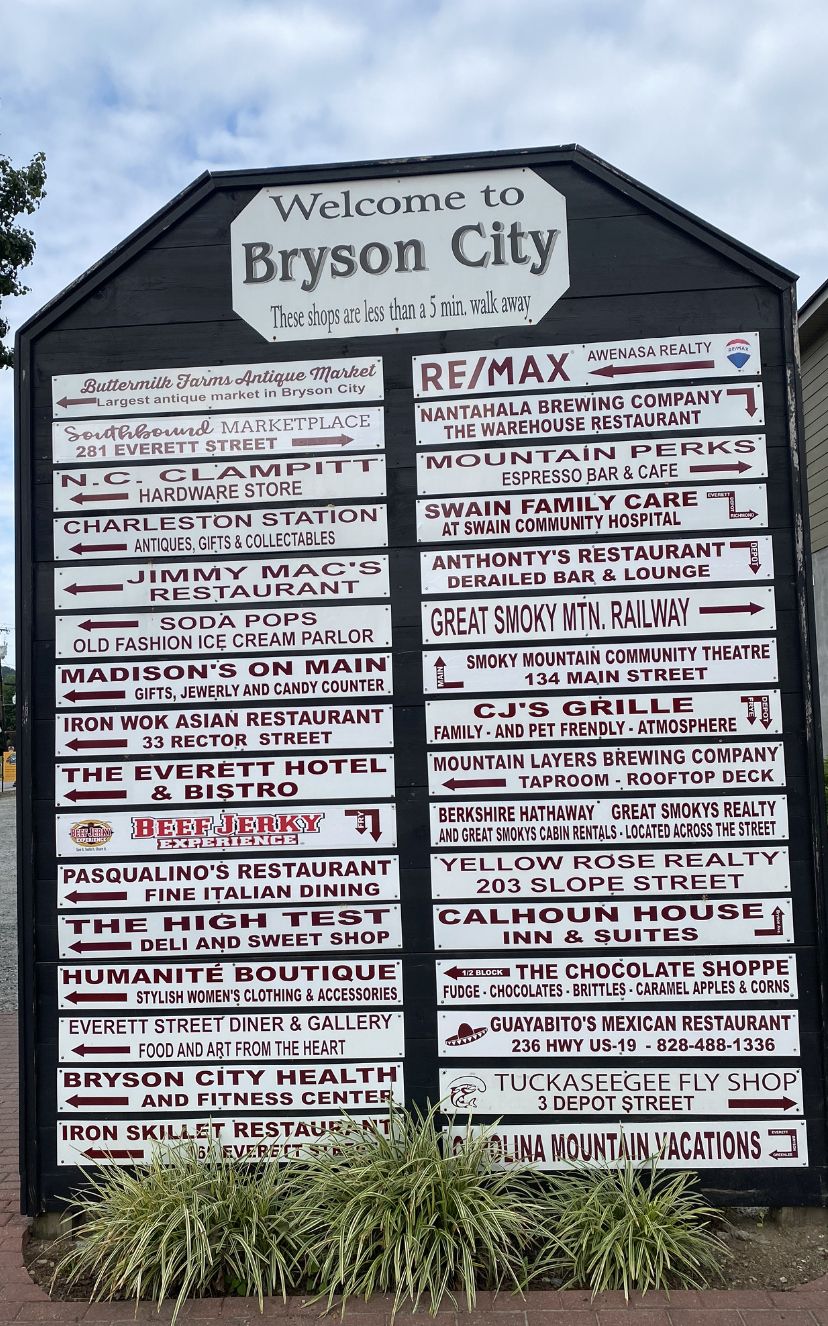 A directional sign for Bryson City with various business names and addresses.