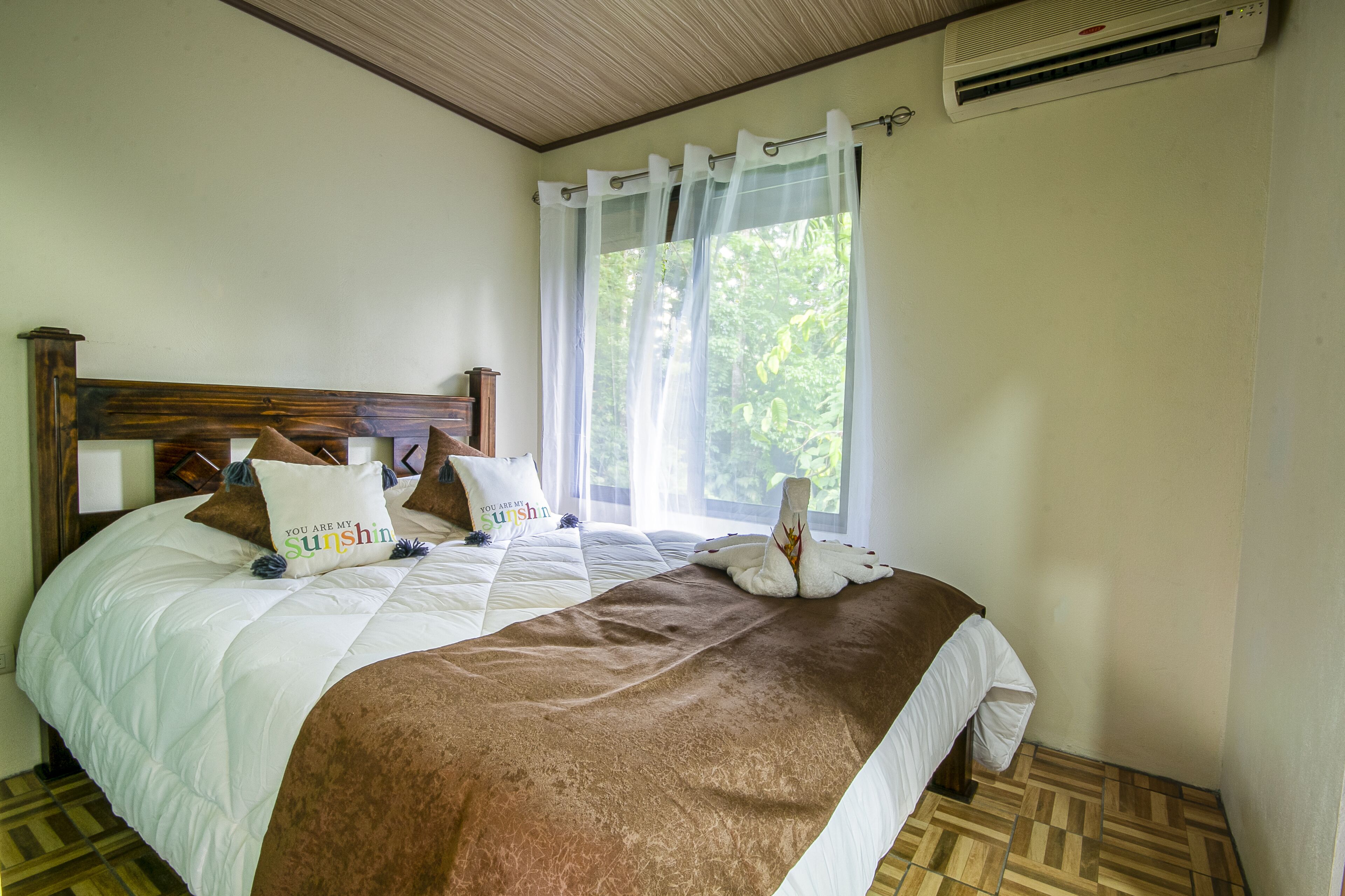 A neatly made bed with a brown blanket, white pillows, and a decorative pillow with text.