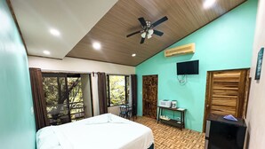 A bedroom with a bed, a ceiling fan, a TV, and a desk with a chair.