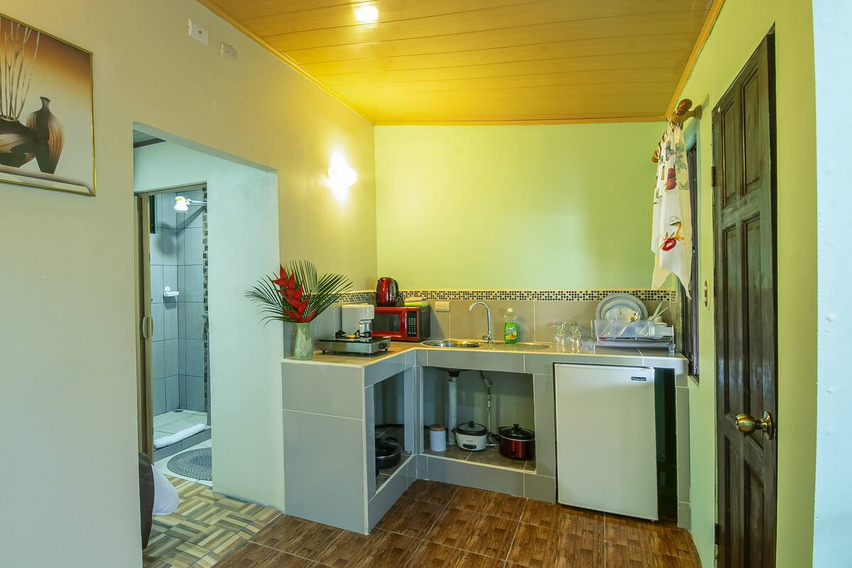 Una cucina compatta con forno a microonde, macchina del caffè e lavandino.
