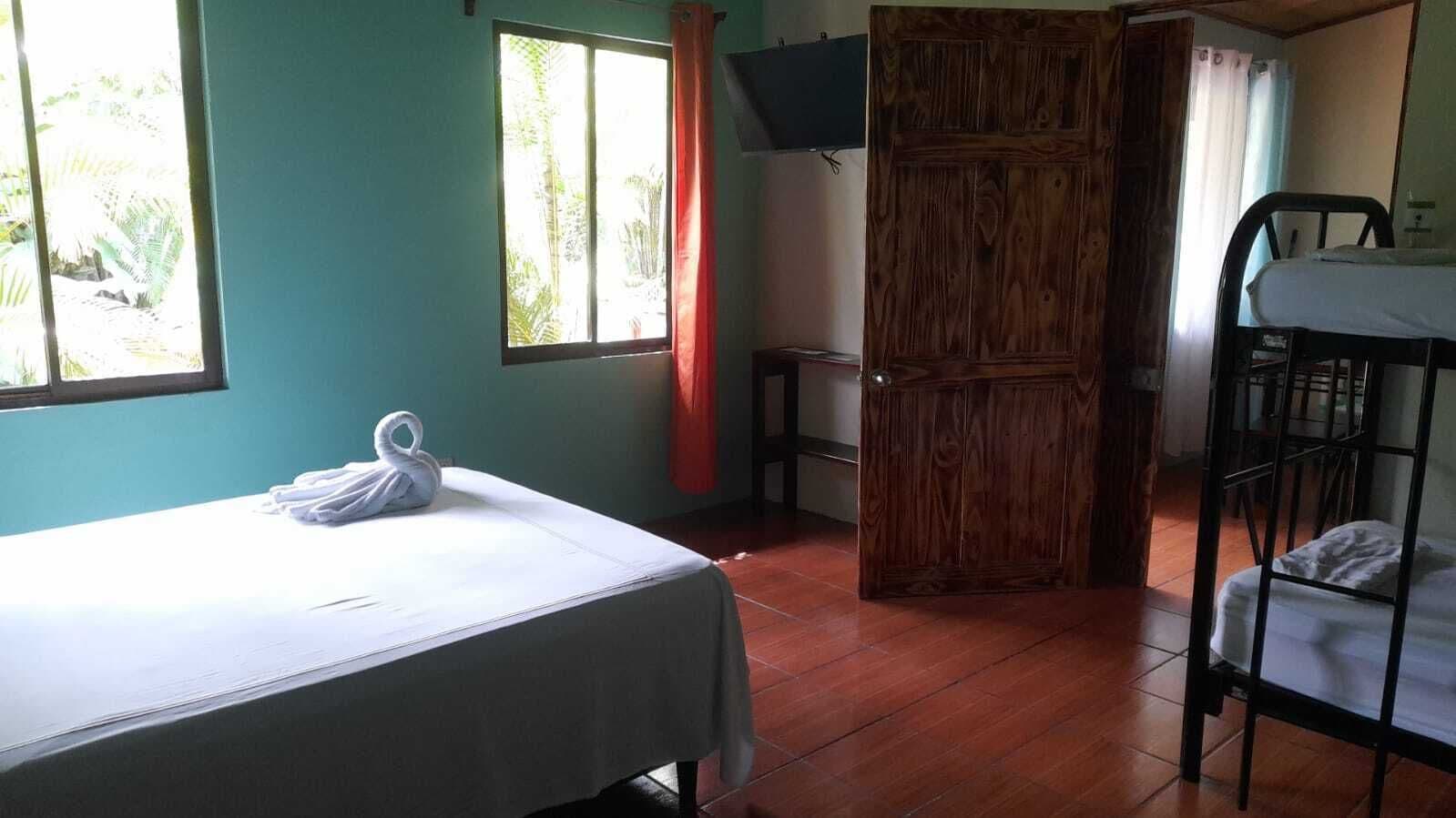Ein Zimmer mit einem Bett, einem Etagenbett, einer Holztür und einem Fenster mit Vorhängen.