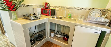 Een kleine keuken met een magnetron, koffiezetapparaat, spoelbak en een koelkast.