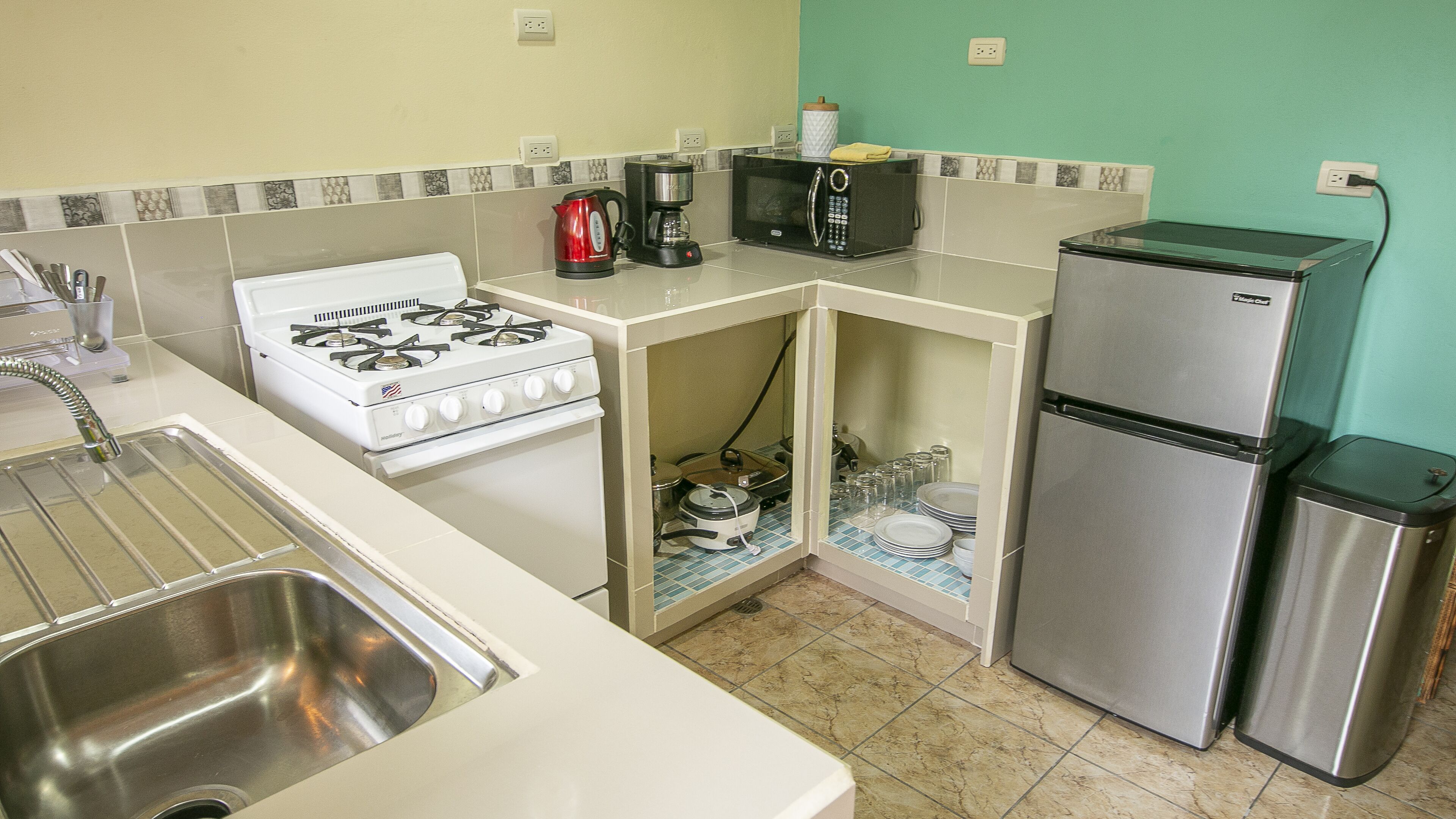 A compact kitchen with a gas stove, a microwave, a coffee maker, and a refrigerator.