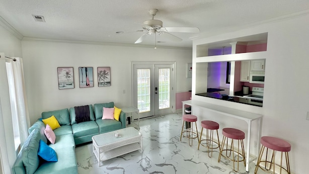 A living room with a green sofa, a coffee table, and a kitchen area with bar stools. - Lovely Home Near Myrtle Beach (Myrtle Beach)