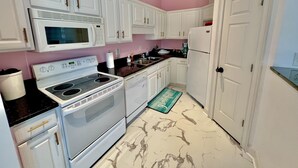 A kitchen with white cabinets, a microwave, stove, and refrigerator. - Lovely Home Near Myrtle Beach (Myrtle Beach)