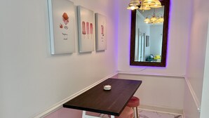A small dining area with a dark wooden table, pink stools, and wall-mounted artwork depicting desserts. - Lovely Home Near Myrtle Beach (Myrtle Beach)