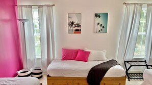 A bedroom with a wooden bed, white bedding, pink pillows, and two wall art pieces. - Lovely Home Near Myrtle Beach (Myrtle Beach)