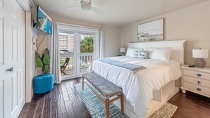 A bedroom with a bed, a bench, a nightstand, a TV, and a view of the outdoors through a sliding door. -  Beach. Walk everywhere. Peaceful. Location. (Navarre)