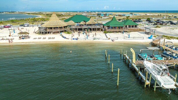 A beachside resort with thatched-roof structures, a sandy beach, and a dock with boats. -  Beach. Walk everywhere. Peaceful. Location. (Navarre)