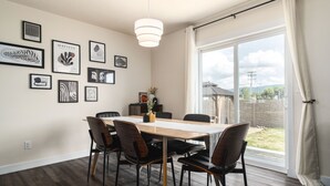 A dining area with a wooden table, black chairs, and framed artwork on the wall.