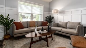 A living room with a sofa set, a coffee table, a floor lamp, and a patterned rug.