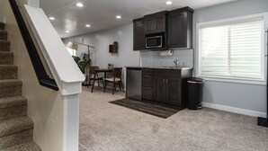 A modern kitchen with dark cabinets, a microwave, and a dining area with chairs and a table.