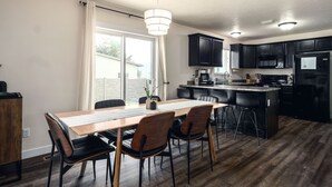A modern kitchen with dark cabinets, a wooden dining table, and black chairs.