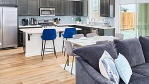 Een moderne keuken met donkere kastjes, een roestvrijstalen koelkast en een centraal kookeiland met barkrukken.