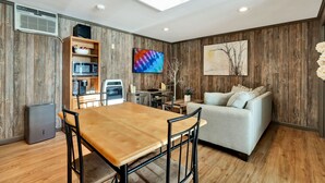 Un espace de vie moderne avec un mur en bois, un coin repas, un canapé et un téléviseur à écran plat.