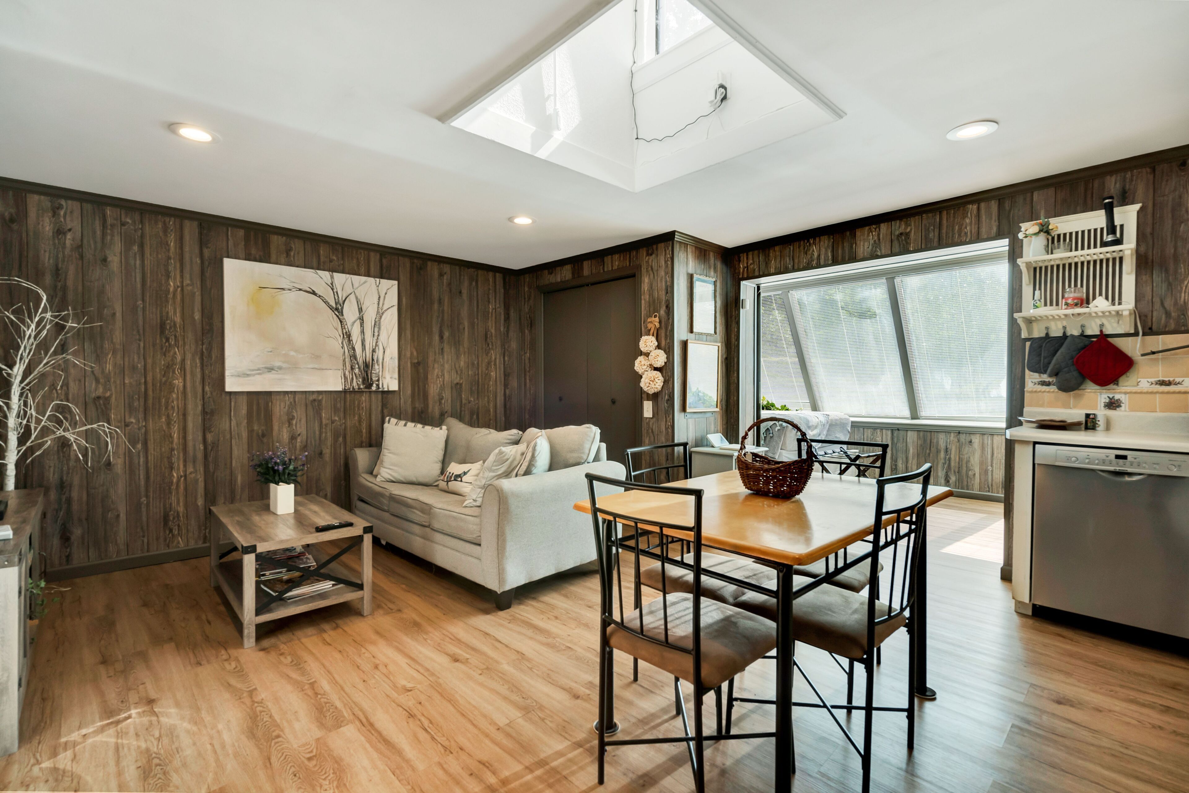 A modern living space with a dining area, sofa, and artwork on the wall.