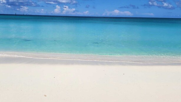 Una playa con agua turquesa cristalina y arena blanca.