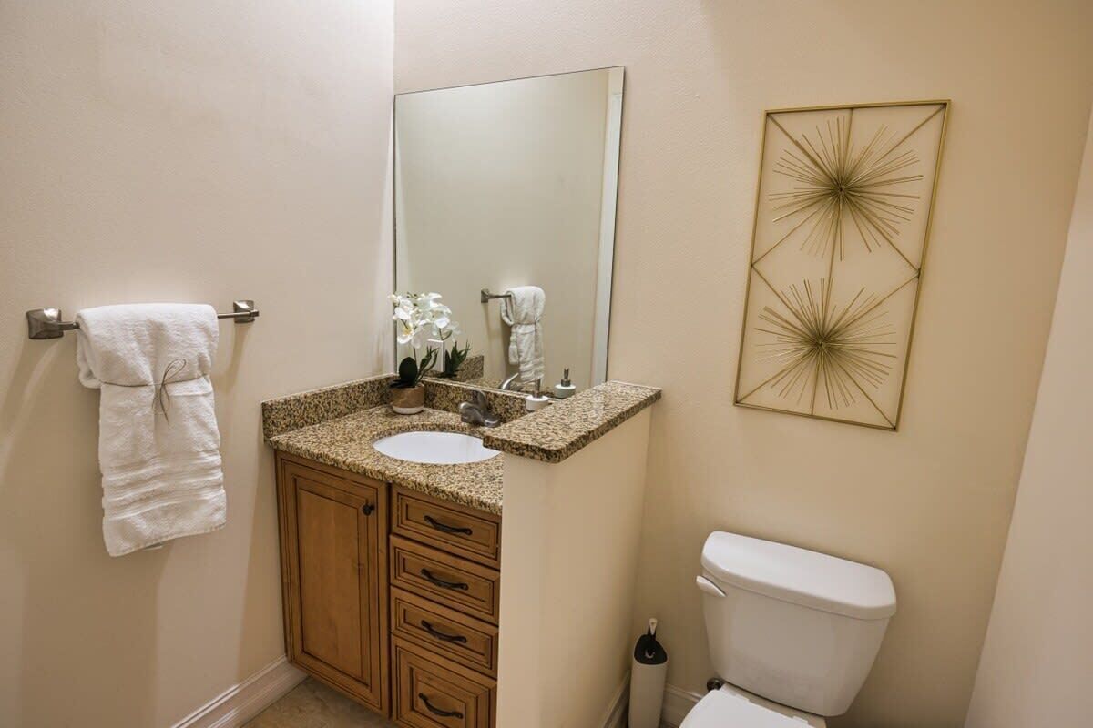 Une salle de bain équipée d’un lavabo, d’un miroir, de toilettes et d’œuvres d’art décoratives sur les murs.