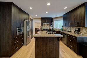 Una cucina moderna con mobili in legno scuro, elettrodomestici in acciaio inossidabile e un'isola centrale.