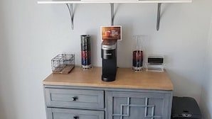 Une petite cuisine équipée d’une machine à café, d’une bouilloire et d’un petit appareil électroménager posé sur le plan de travail.