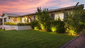 Una casa moderna con un prato curato, un'ampia finestra e un giardino ricco di piante e fiori.