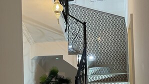 Eine Treppe mit gemusterten Geländern und einem Blumentopf am Fuß.